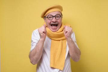 Wow concept. Attractive hispanic man in yellow beret and scarf standing with opened a little mouth...
