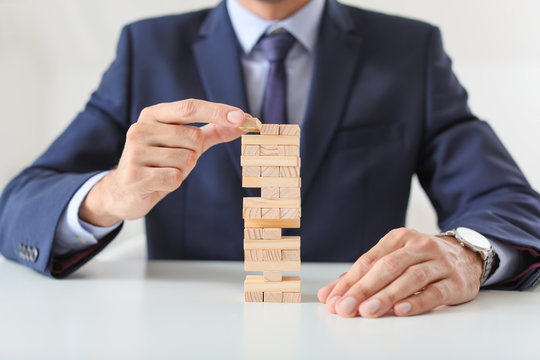 Businessman manager building tower from blocks at table. Concept of planning, risk and strategy in business
