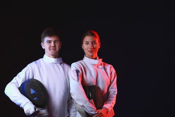 Toned photo of young fencers on dark background