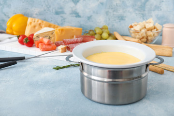 Tasty cheese fondue on color background