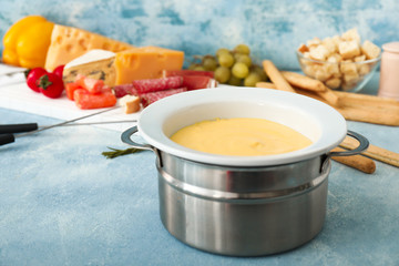 Tasty cheese fondue on color background