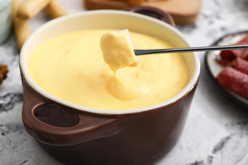 Dipping of crouton into cheese fondue, closeup