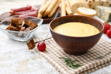 Bowl with cheese fondue and snacks on table