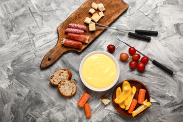 Cheese fondue with snacks on grey background