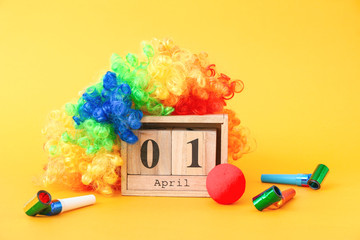Calendar with date of April Fool's Day and party decor on color background
