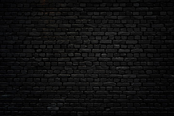 Zwarte bakstenen muur als achtergrond of behang of textuur