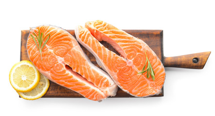 Board with raw salmon steaks on white background