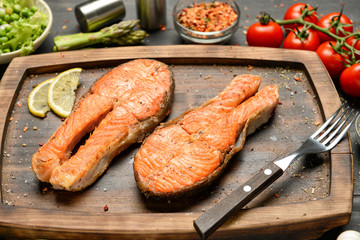 Tasty fried salmon on wooden board