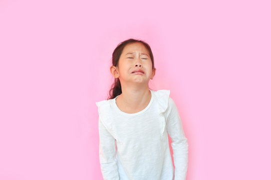 Portrait asian little girl crying isolated on pink background. Angry kid with sad expressions and screaming