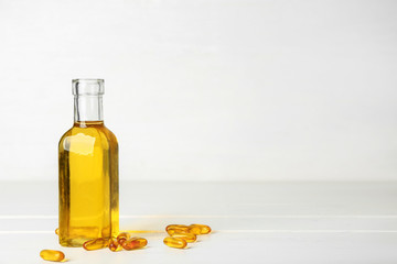 Bottle of fish oil and pills on white background