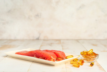 Plate with fish and oil pills on white table