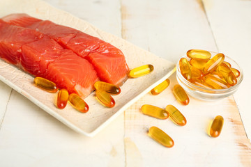 Plate with fish and oil pills on white table