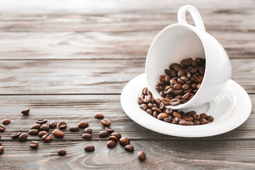 Cup with coffee beans on wooden background