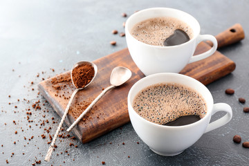 Cups of hot coffee on grey background