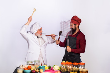 Cook. Chef. Two chefs fighting on kitchen. Professional culinary. Bearded man in kitchen apron. Bearded man chef in uniform. Ready to cook. Healthy lifestyle. Diet. Healthy food. Health care.