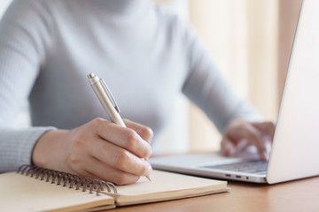 Hand of business women using laptop and write notebook while sitting working on the desk in the...