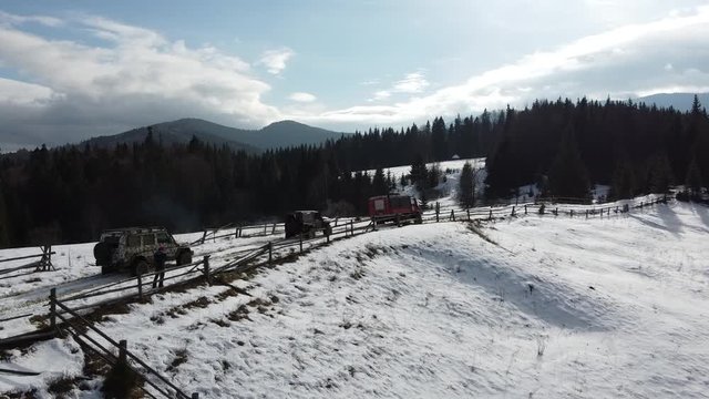 A group of SUVs rides through a snowy meadow on top of a mountain