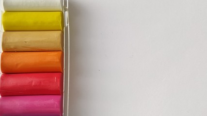 Multi-colored plasticine in plastic packaging on a white background