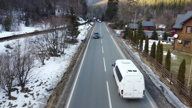 A road and a railway run along the edge of the river, in a village in the highlands