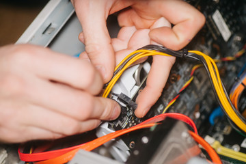 Professional system administrator holds in hands sockets connectors of standard power supply unit. man repairing and assembling computer. concept of repair computer. Selective focus