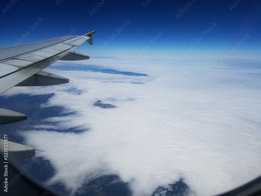 Wall mural wing of an airplane flying above the clouds