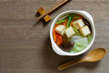 top view of fish tofu clear soup in a ceramic bowl on wooden table. asian homemade style food concept.