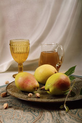 Still life with winter pears on a dish with two glasses