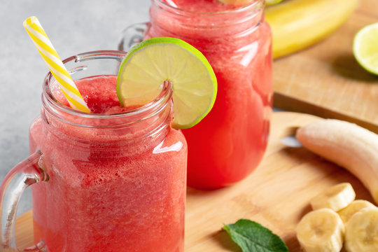 Watermelon smoothie with banana, lime and mint in mug jars on a cutting board. Healthy eating concept