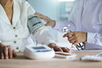 Doctor with stethoscope taking care and checking blood pressure of elderly woman patients in hospital background, medical and healthcare of elderly.