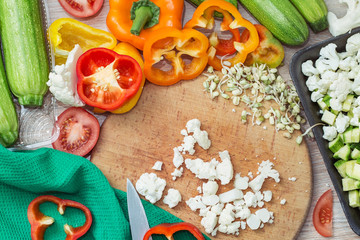 Fresh vegetables on a cutting Board top view, slicing peppers, zucchini, tomatoes and cauliflower...