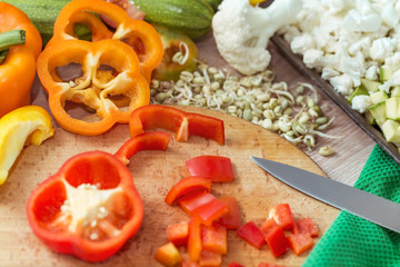 Slicing peppers, zucchini, tomatoes and cauliflower on a cutting board