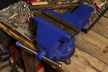 Blue vise on a wooden table. Bench tools. Vice.