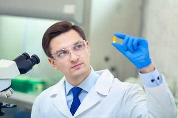 Scientist studies properties and benefits of omega 3 fatty acids using microscope and laboratory...