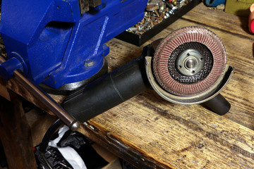Angular grinding machine. Blue vise on a wooden table. Bench tools. Vice.