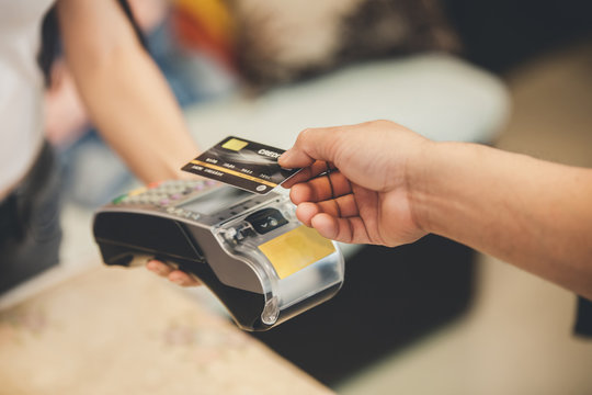 Retail, credit card payment service. Customer paying for order Product. Woman paying with card contactless in the shop store. Close-up view on the terminale and card