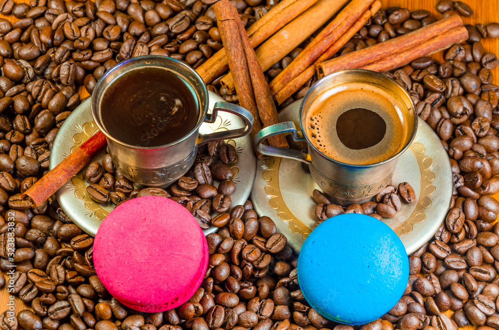 Poster two metal coffee cups with coffee beans and macaroni cookies.