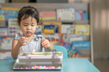 Little girl concentrated on beaded activity  at home.