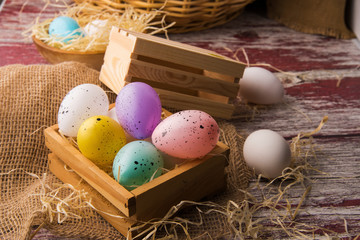 Easter eggs in a wooden box on a textured background