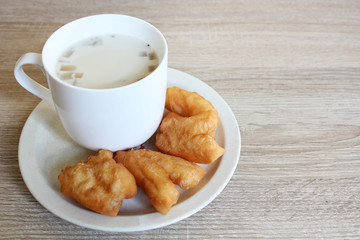 Soybean milk with millet, jelly and chia seed served with deep-fried dough stick on wooden background.