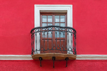 Colonial style balcony with wooden window, wrought iron decorations and red facade, Potosi, Bolivia.