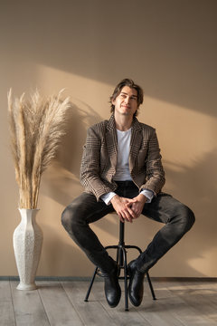 Tall Handsome Man Sitting On Bar Chair In A Daylight From Window