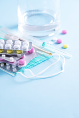 Concept of therapy, prevention of virus flu, viral attack, colds pills, antibiotics and vitamins, protective medical face masks over blue background. Coronavirus Covid-19. Copy space