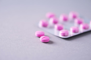 Obraz na płótnie Canvas Pink capsule, pills, vitamins on grey background. Copy space. Bunch of drugs, cold flu treatment. Women disease treatment. Banner