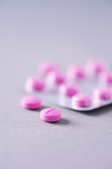 Obraz na płótnie Canvas Pink capsule, pills, vitamins on grey background. Copy space. Bunch of drugs, cold flu treatment. Women disease treatment. Banner