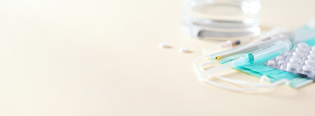 Bunch of drugs, cold flu treatment. Viral attack. Set for flu treatment - pills, capsules, thermometer, protective surgical mask, syringe. Copy space. Banner. Coronavirus Covid-19