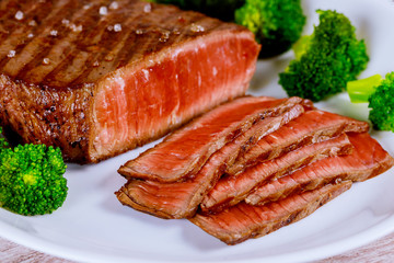 Sliced grilled rare beef steak served with broccoli.