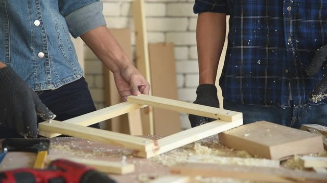 Young Asian group man carpenter worker measuring and preparing to cut wood plank for build diy furniture in workshop