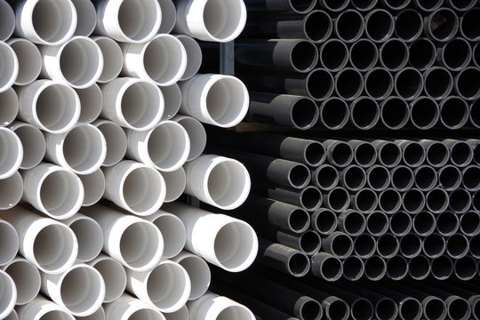 Close-up front view of stacks of black and white plastic water pipes 