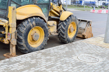 Fototapeta premium Big bright yellow powerful industrial heavy excavator tractor, bulldozer, specialized construction equipment for road repair during the construction of a new micro-district in a big city