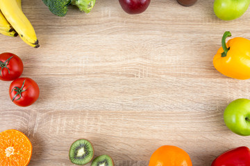 Frame of fresh colorful vegetables and organic fruits on wooden background. Top view with copy space for text. Cooking ingredients, healthy food and nutrition concept.